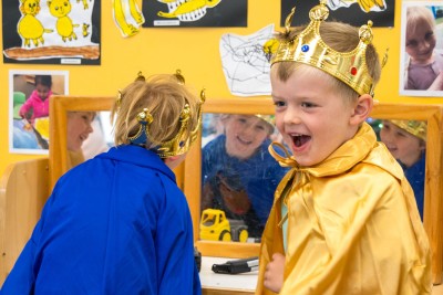 Two children dress in crowns and capes.